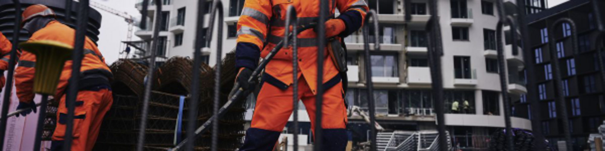 Construction worker on a construction site compacting concrete with a Wacker Neuson internal vibrator.