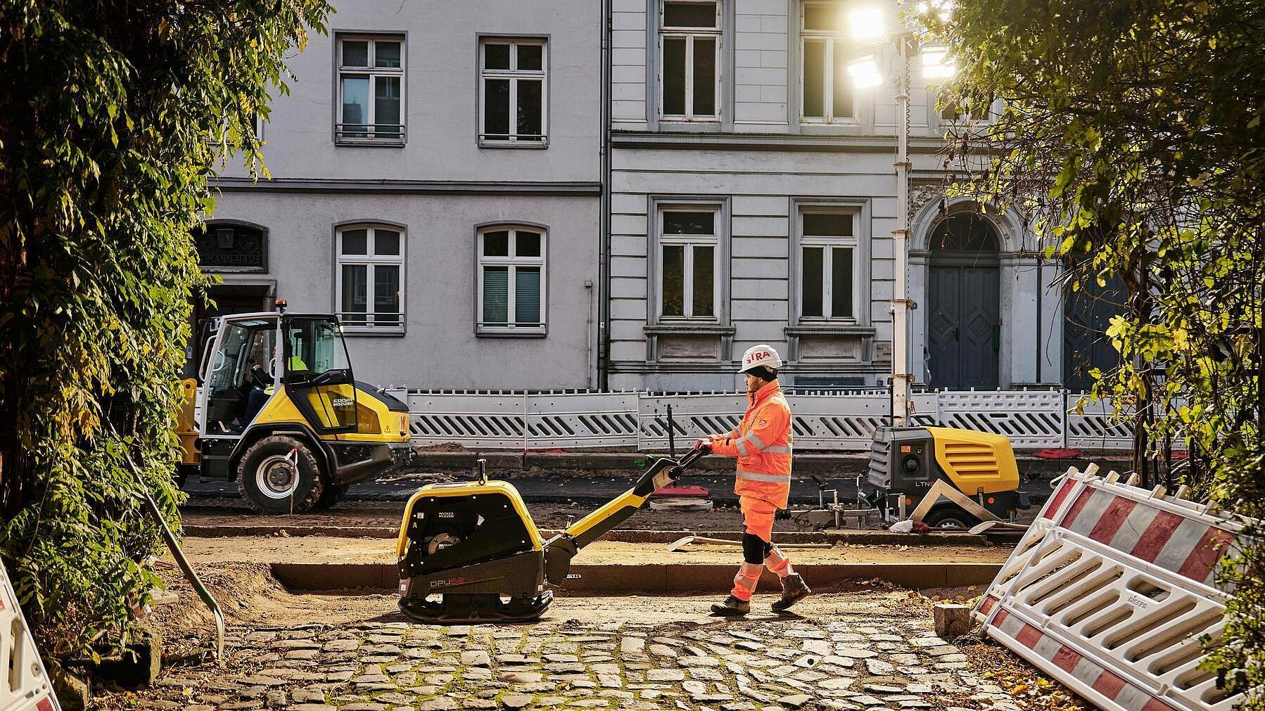 Man working with dumper on road with old expensive houses in the background