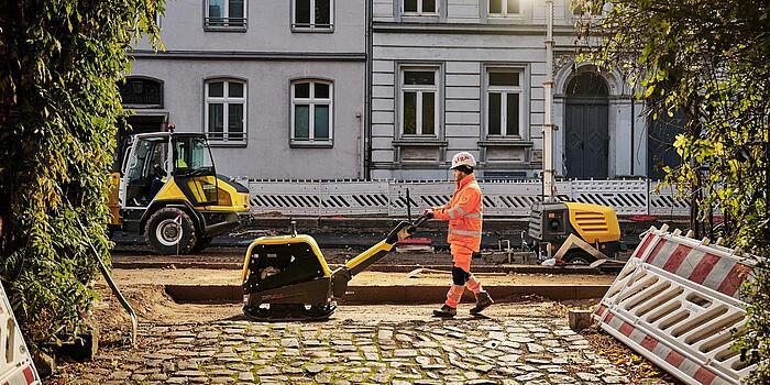 Man working with dumper on road with old expensive houses in the background