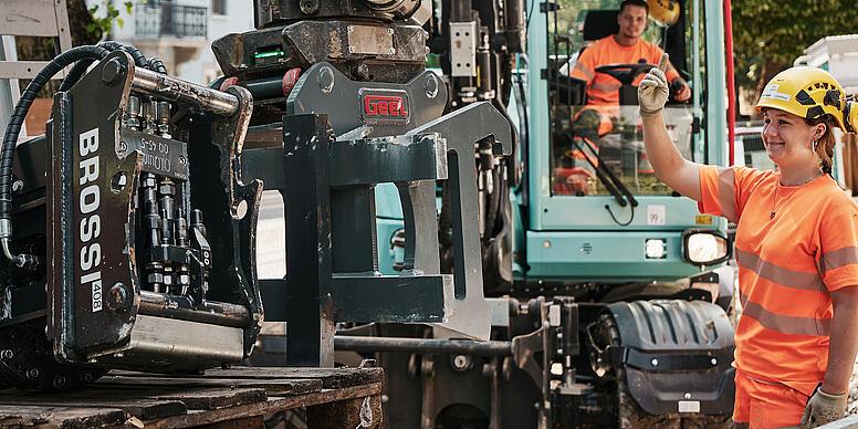 Egy városi építkezésen egy gépkezelő egy Wacker Neuson EW100 kerekes kotrógépen szerel fel egy hidraulikus mellékberendezést.