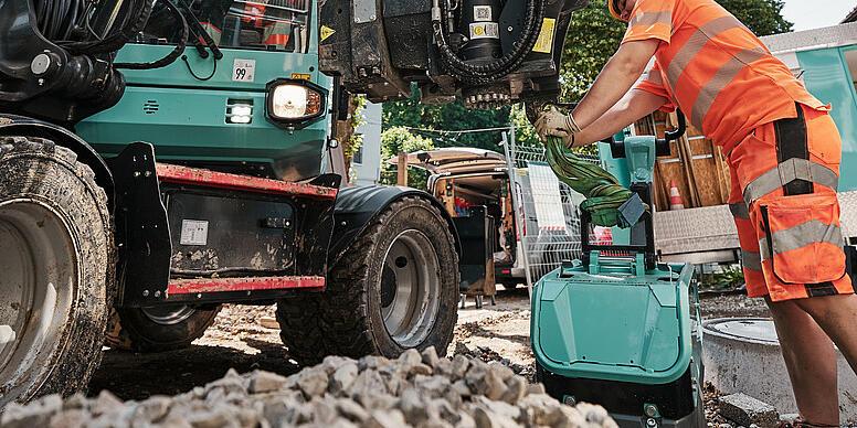 Egy gépkezelő egy Wacker Neuson EW100 kerekes kotrógépen cseréli a munkaszerelvényt az építkezésen.