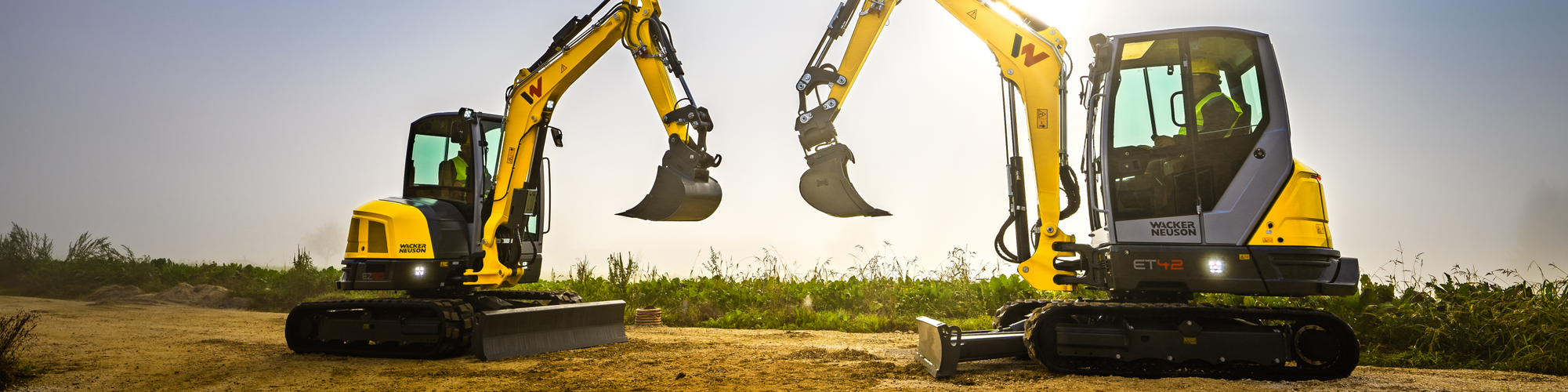 Two Wacker Neuson tracked excavators standing on a construction site.
